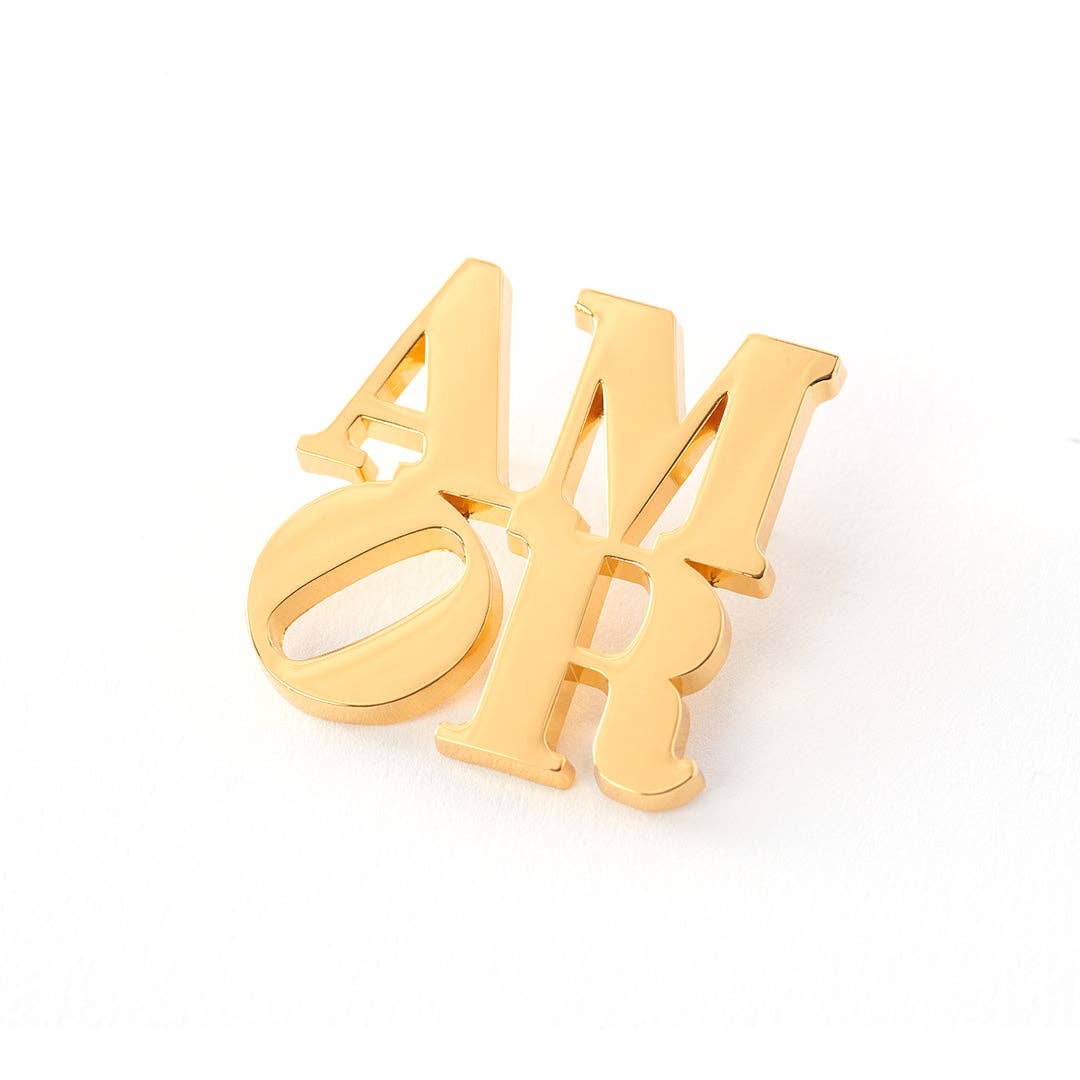 Officially licensed Robert Indiana AMOR enamel pin featuring the iconic stacked lettering in a polished gold finish.