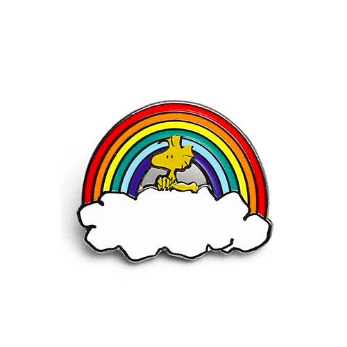 Official Peanuts Woodstock enamel pin featuring Woodstock standing beneath a colorful rainbow resting on white clouds.