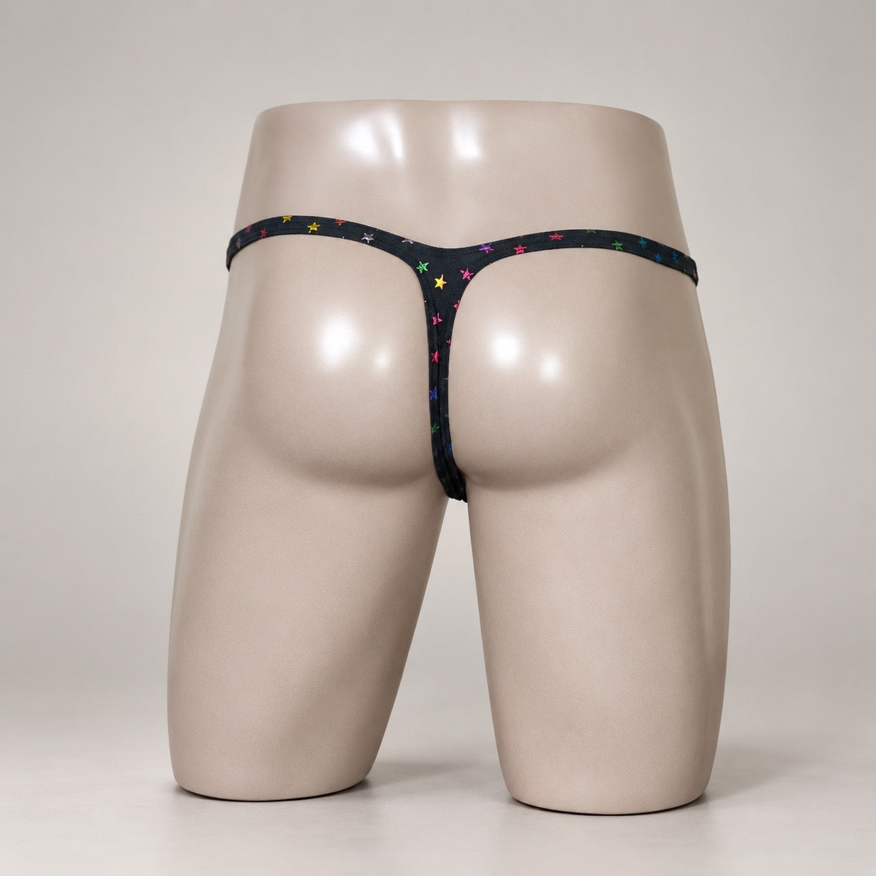 Rear View of Rainbow Stardust black and rainbow star-print men’s Muscle thong by PapiMalo Gear