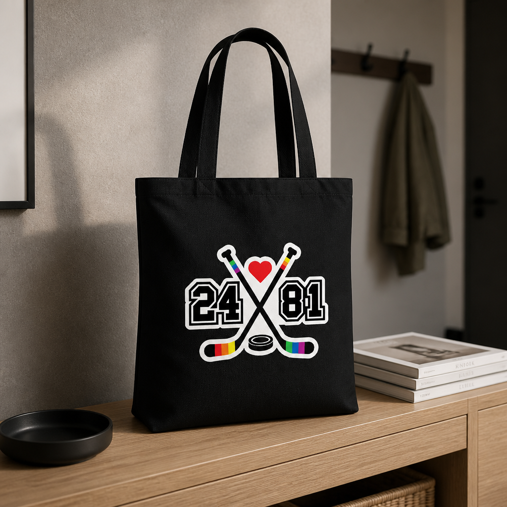 Black Heated Rivalry inspired tote bag with rainbow hockey stick 24/81 design and heart graphic on a table