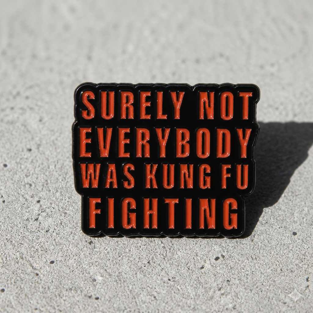 Surely Not Everyone Was Kung Fu Fighting enamel pin with bold red text design on a concrete surface
