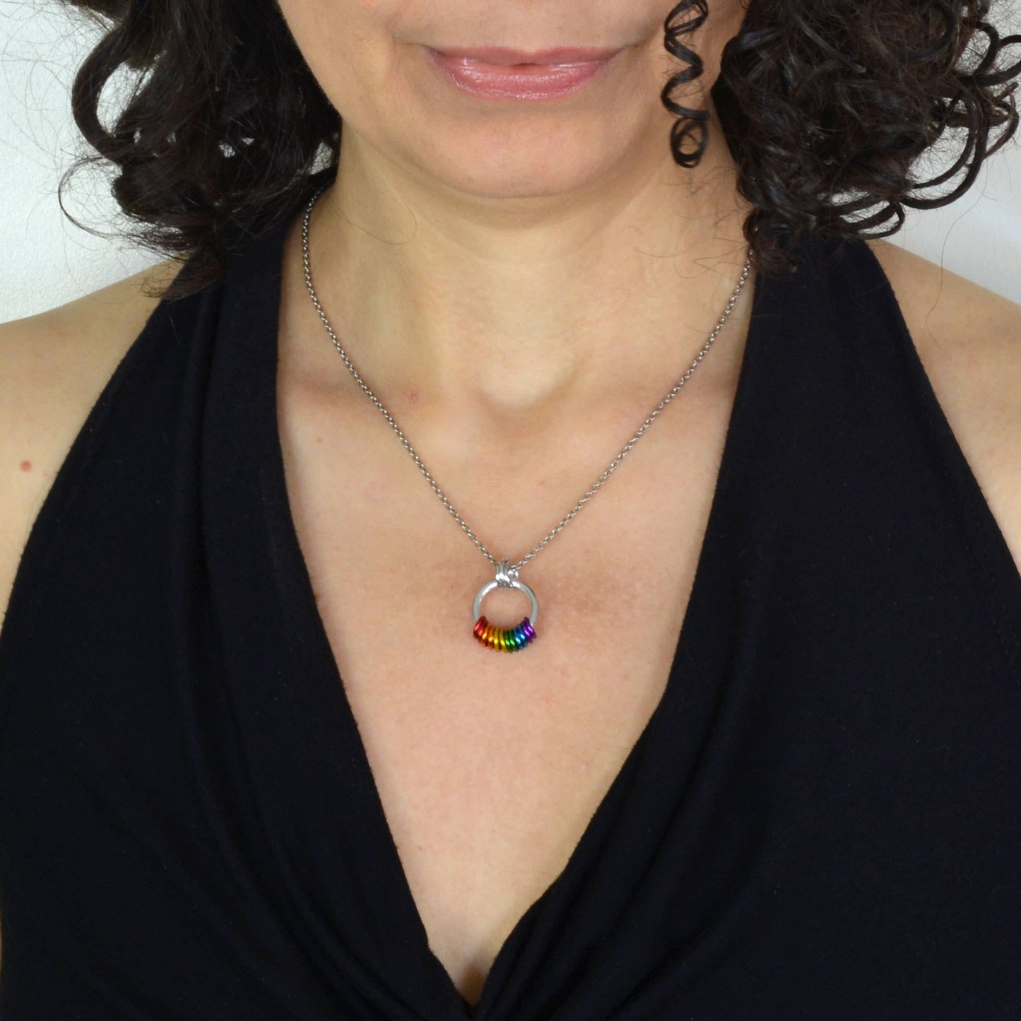 woman wearing a Handcrafted LGBTQ+ rainbow minimalist coil fidget necklace featuring twelve free-spinning aluminum rings on an adjustable stainless steel chain.