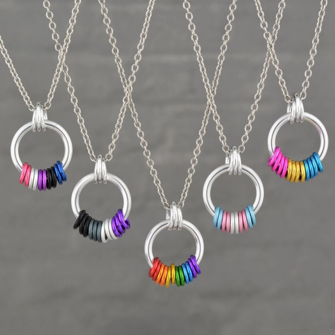 Assorted Pride Coil Fidget Necklaces featuring colorful identity-inspired coil designs on silver-tone circle pendants
