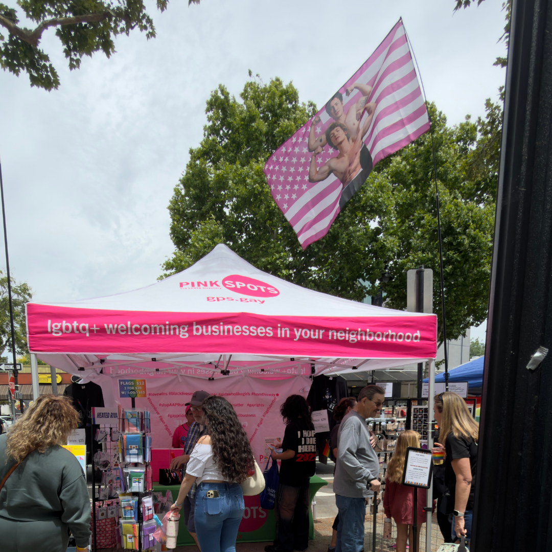 Large Heated Rivalry fan-inspired wall flag featuring vibrant hockey romance artwork with metal grommets for hanging, flying high above our booth at Suisun Pride Festival in May, 2026