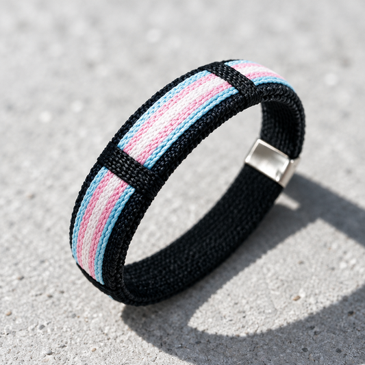 Trans pride woven cuff bracelet with pastel blue pink and white stripe design displayed on a concrete surface