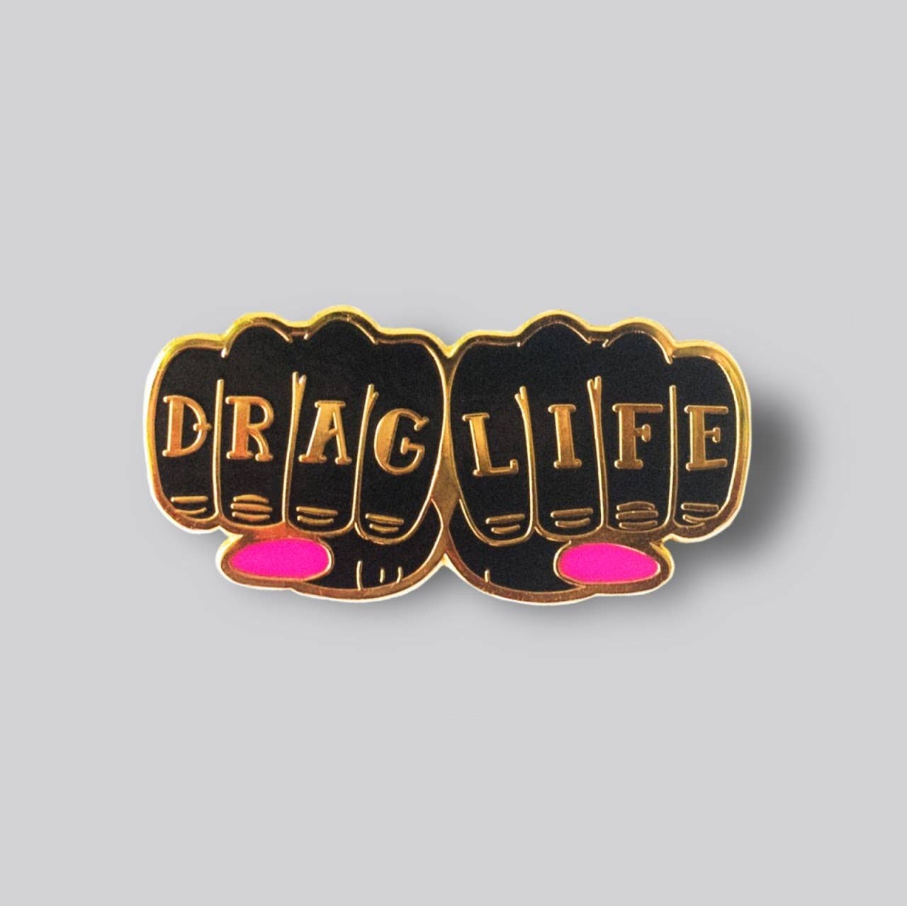 Drag Life enamel pin featuring gold-tone knuckle lettering with pink accent details