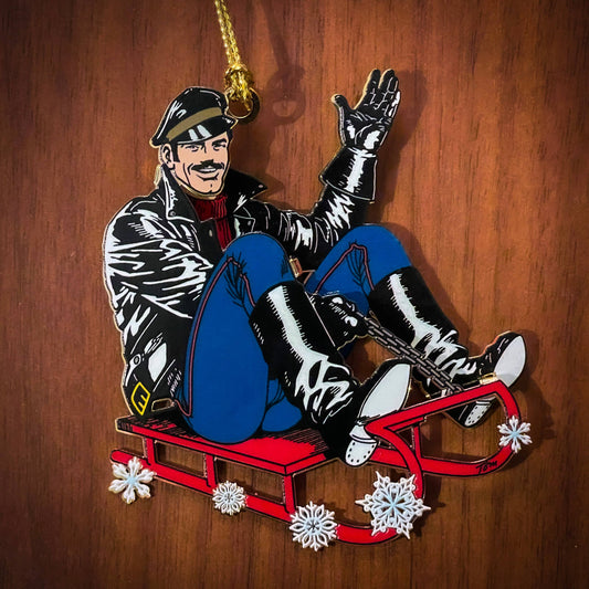 Limited edition Tom of Finland leather sled metal ornament featuring a leather-clad character riding a red sled