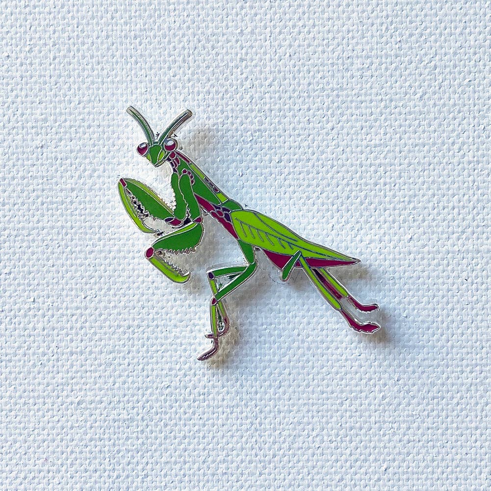Silver-plated hard enamel pin featuring a detailed green and pink praying mantis insect design on a textured white background