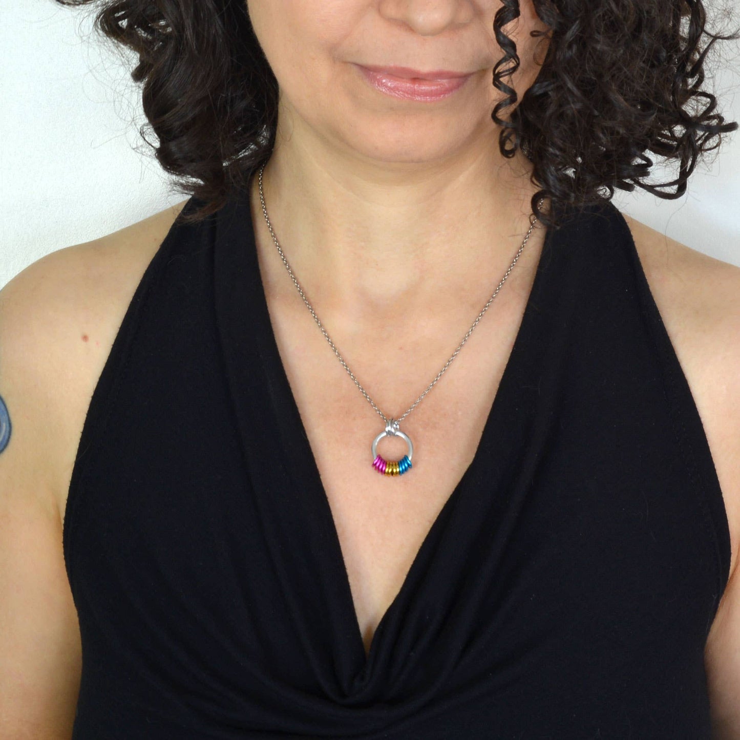 woman wearing a Handcrafted Pansexual Pride coil fidget necklace featuring free-spinning pink, yellow, and blue aluminum rings on an adjustable stainless steel chain.