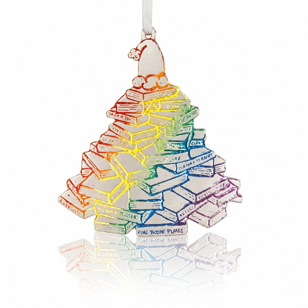 Handmade pewter holiday ornament shaped like a Christmas tree made from stacked books with rainbow-colored accents.
