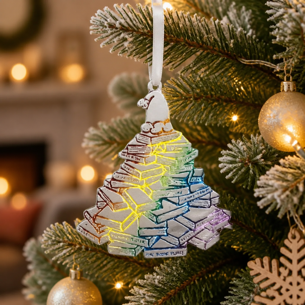 Handmade pewter holiday ornament shaped like a Christmas tree made from stacked books with rainbow-colored accents.