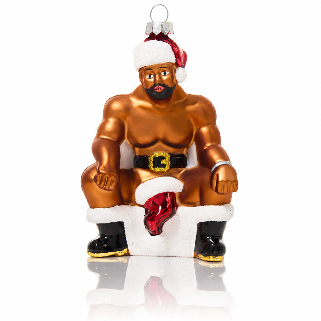 Hand-painted glass Christmas ornament featuring a muscular bearded Santa sitting on the naughty stool wearing a Santa hat and boots.