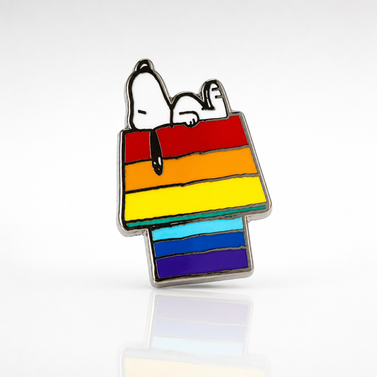 Official Peanuts enamel pin featuring Snoopy resting on a rainbow-colored doghouse
