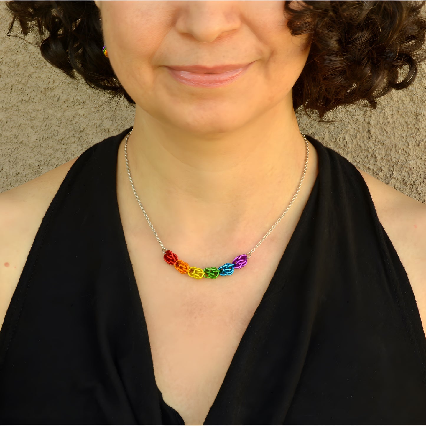 Hand-linked rainbow chainmail necklace featuring colorful aluminum rings on an adjustable stainless steel chain, worn by a model around the neck