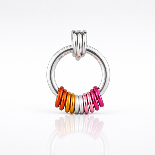 Handcrafted Lesbian Pride minimalist coil fidget necklace featuring free-spinning orange, white, pink, and magenta aluminum rings on an adjustable stainless steel chain on a white background