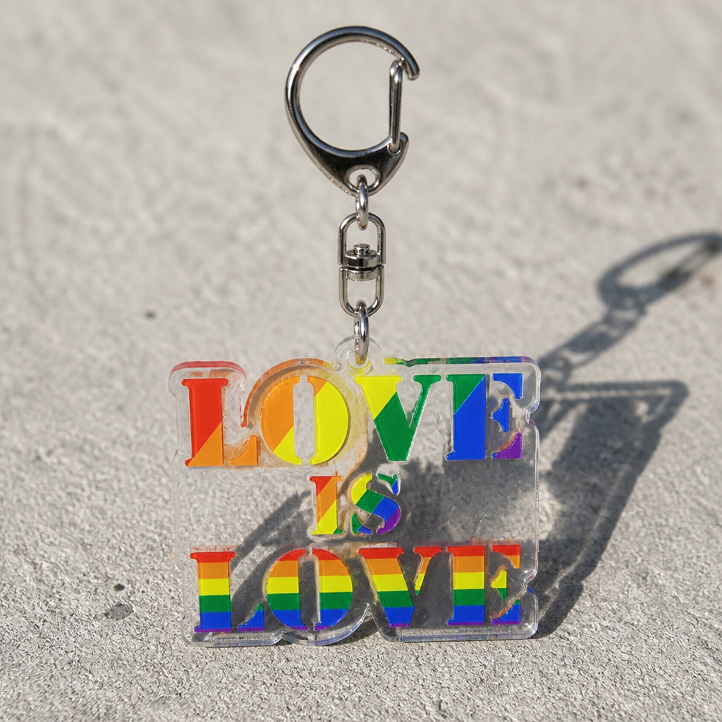 Love Is Love rainbow acrylic keychain with LGBTQ pride colors on a concrete surface
