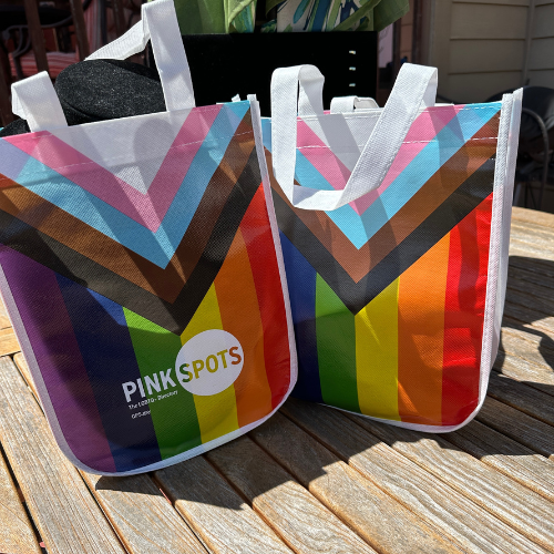 Reusable Progress Pride tote bag with colorful inclusive flag design and white handles