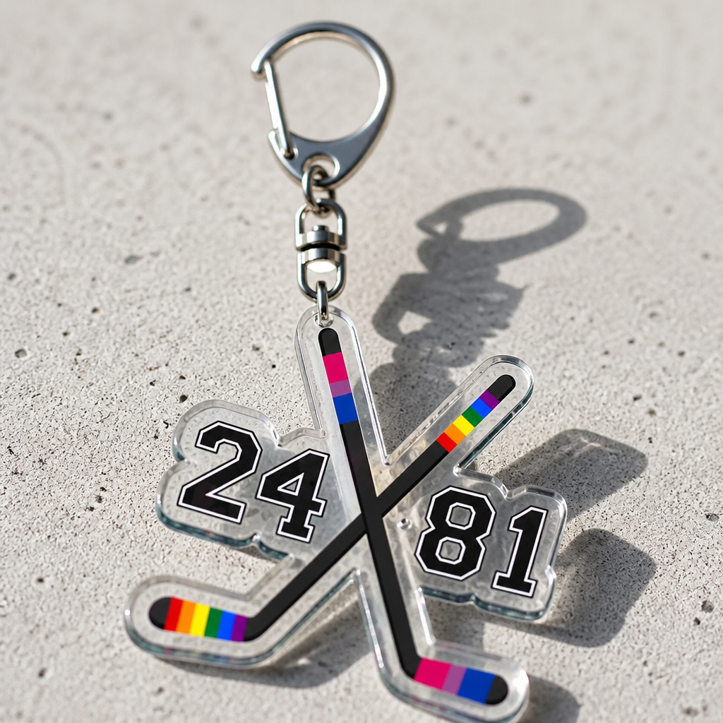 Heated Rivalry acrylic keychain with crossed rainbow hockey sticks and Hollander Rozanov numbers on a concrete surface