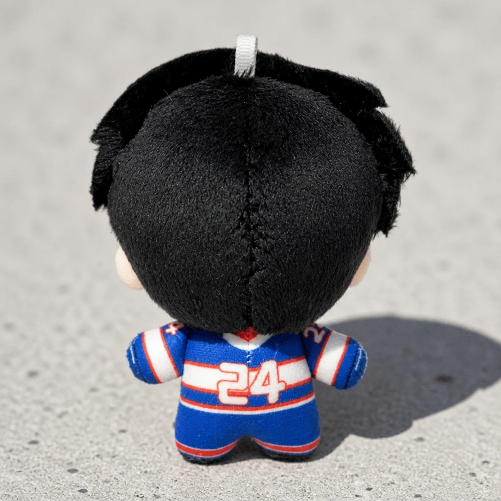back view of Heated Rivalry Hollander chibi-style plush keychain wearing blue hockey uniform on a concrete surface
