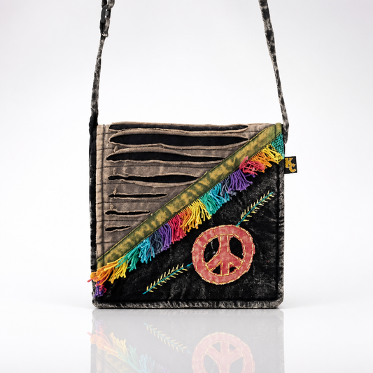 Vintage-inspired black crossbody bag featuring an embroidered peace sign, colorful rainbow fringe accents, and decorative razor-cut detailing.