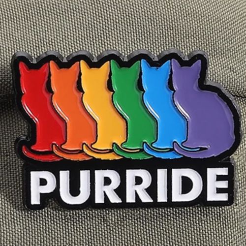 Purride Cats enamel pin featuring six rainbow-colored cat silhouettes in Pride colors on textured fabric