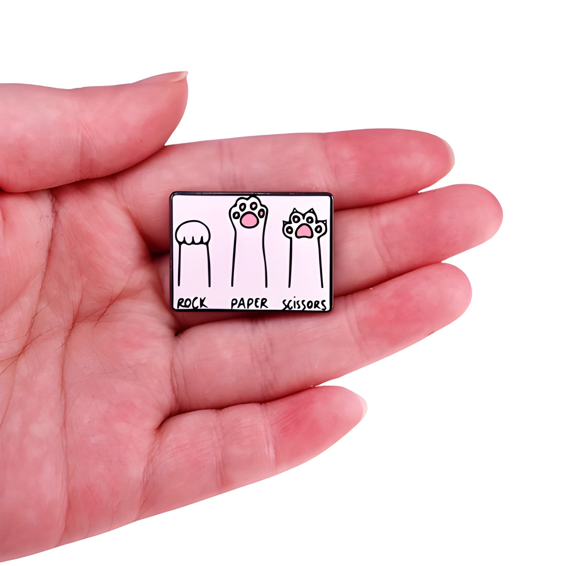 Cats Playing Rock Paper Scissors enamel pin featuring kitten paws and claws design held in a hand