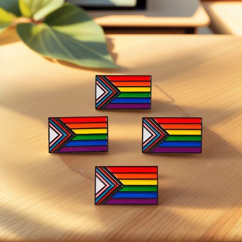 Four Progress Pride Flag enamel pin with vibrant inclusive LGBTQ+ Pride flag colors on a wooden surface