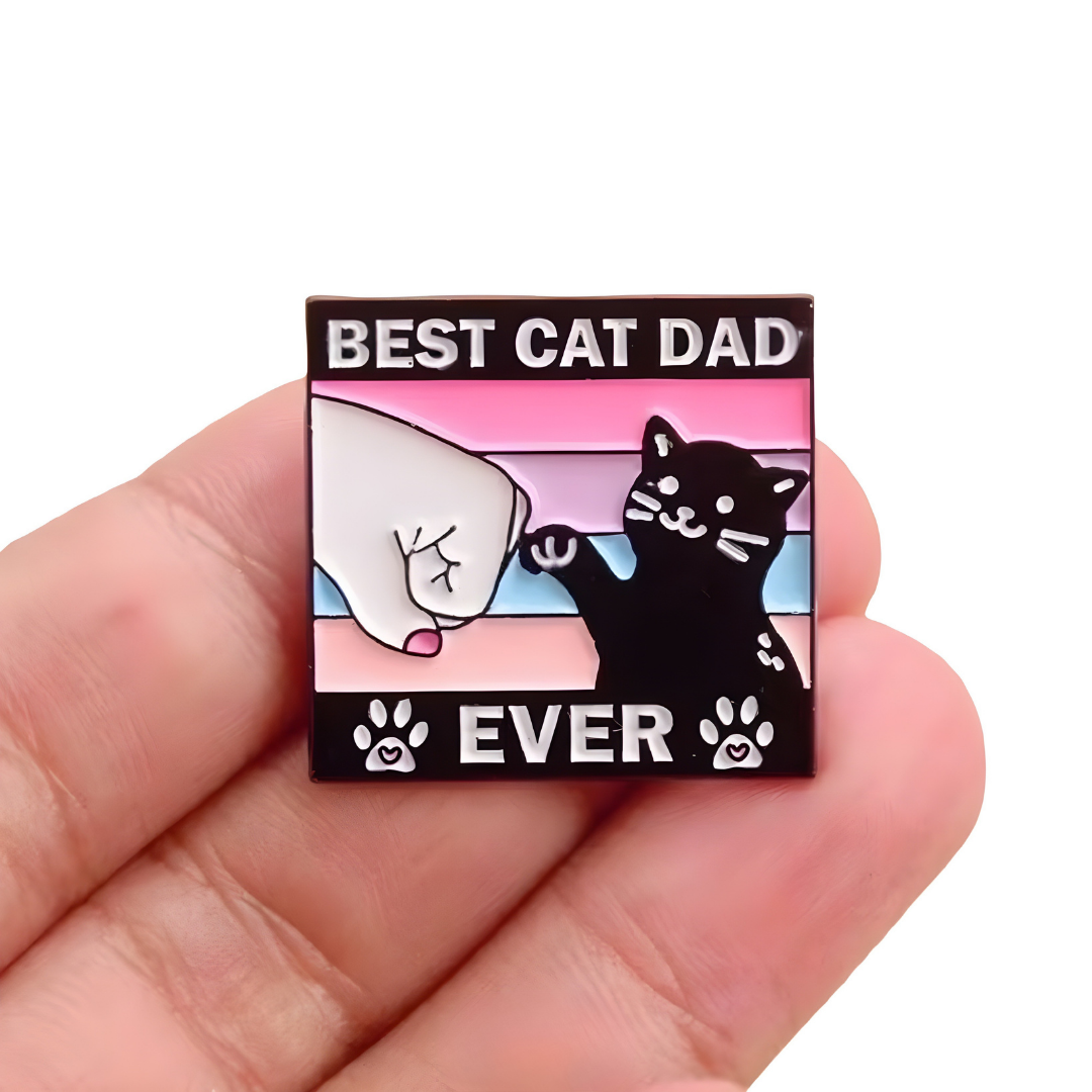 Best Cat Dad Ever enamel pin featuring black cat and pastel fist-bump design held between 3 fingers
