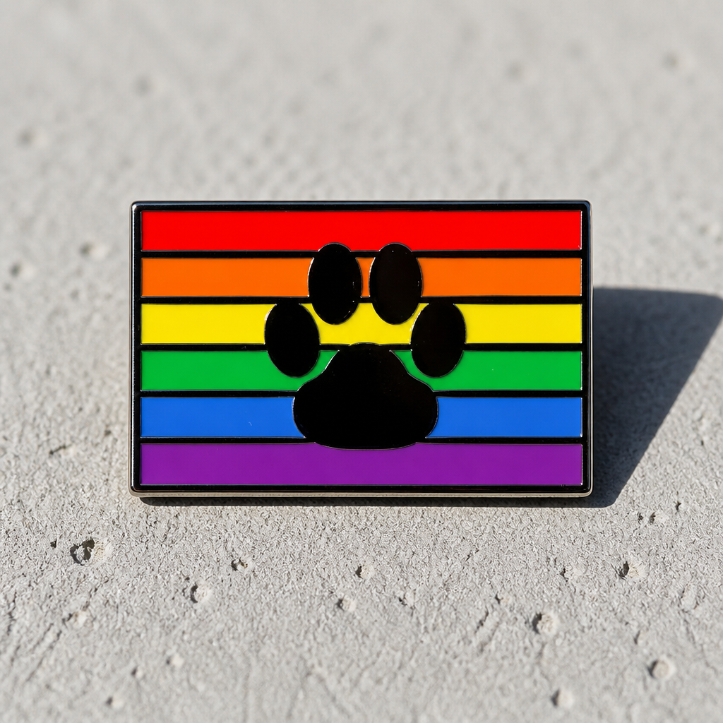 Rainbow Paw Pride enamel pin with black paw print over classic rainbow Pride flag colors on a concrete surface