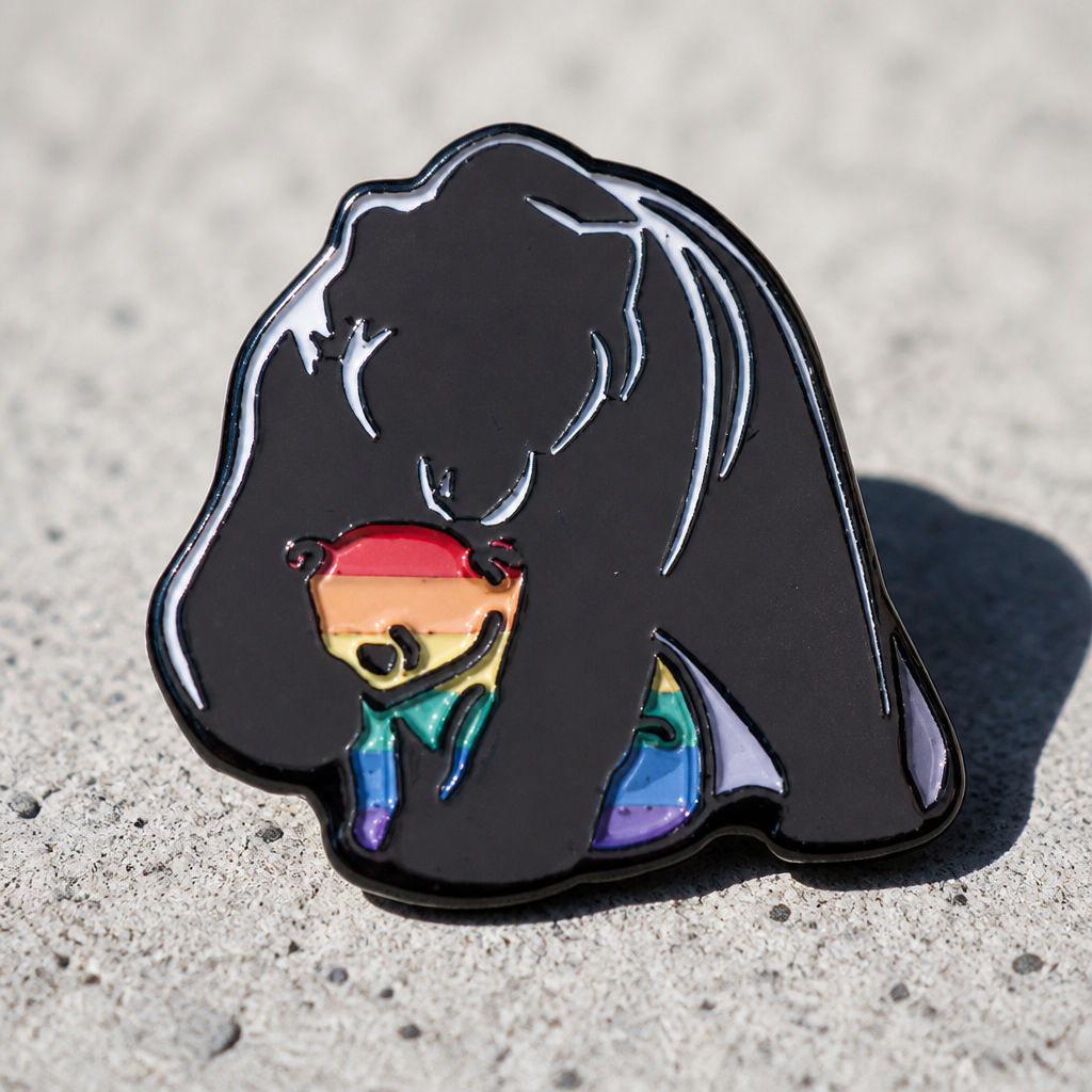 Mama bear enamel pin hugging a small rainbow Pride cub on a concrete surface