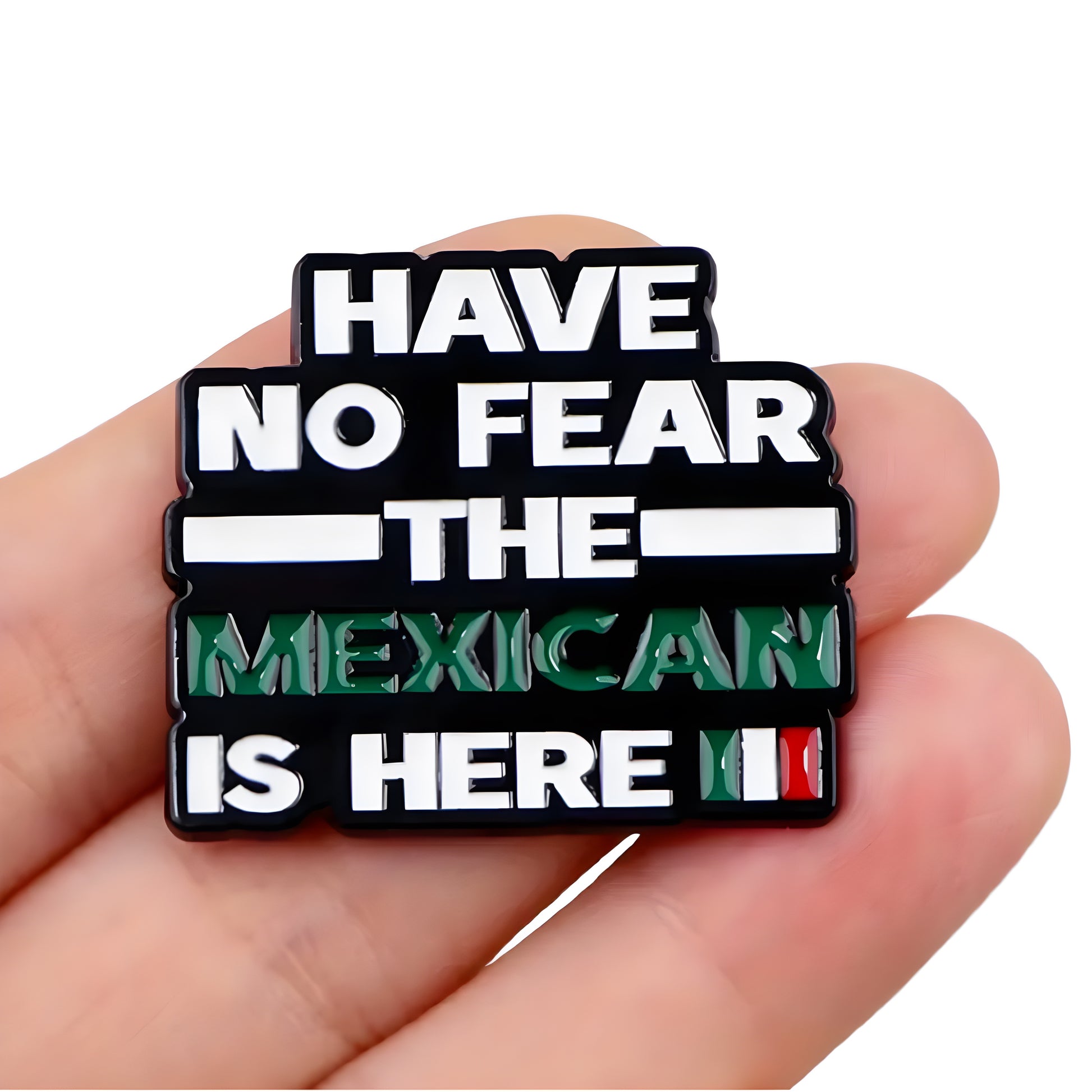 Black enamel pin with “Have No Fear The Mexican Is Here” text and Mexican flag colors held between a hand