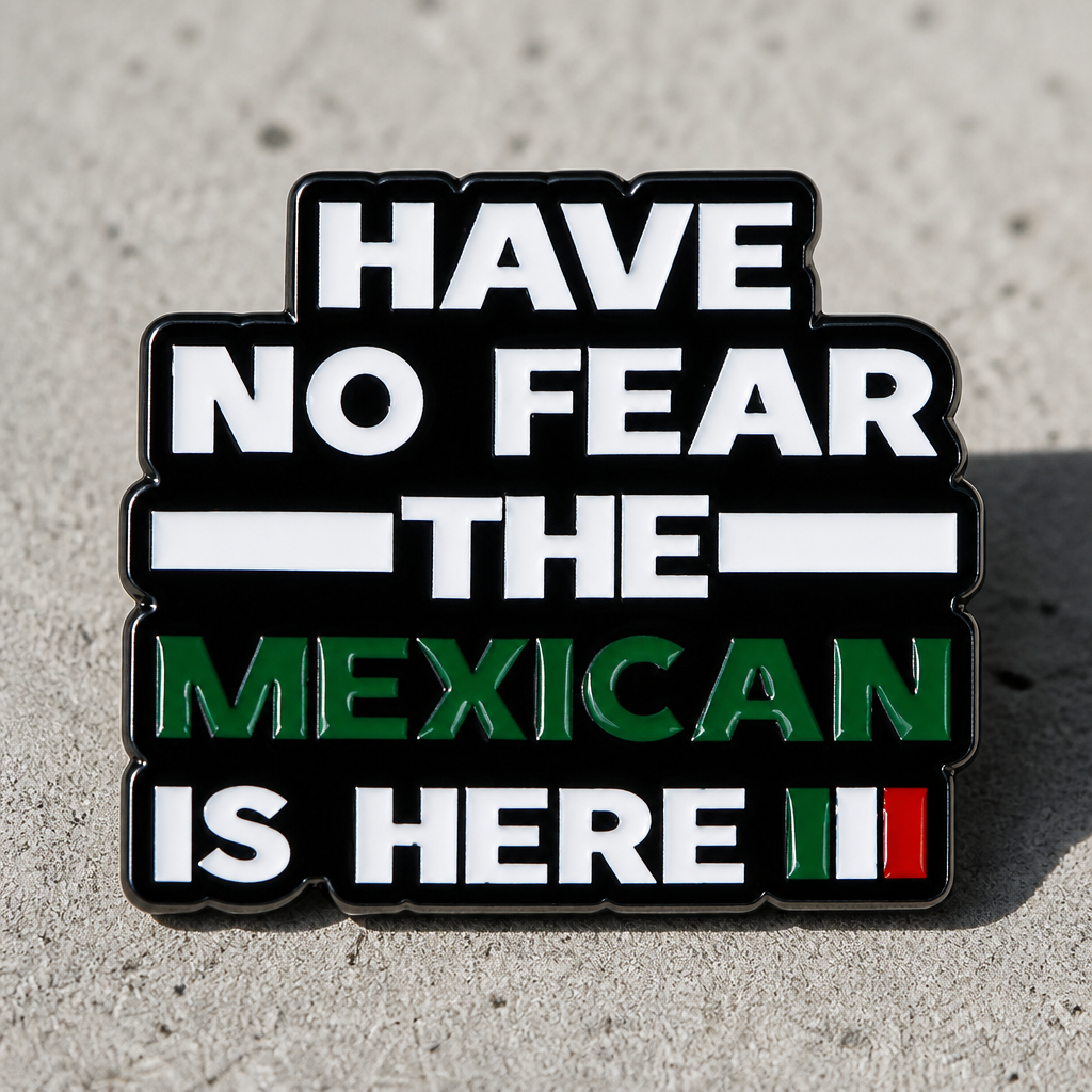 Black enamel pin with “Have No Fear The Mexican Is Here” text and Mexican flag colors on a concrete surface