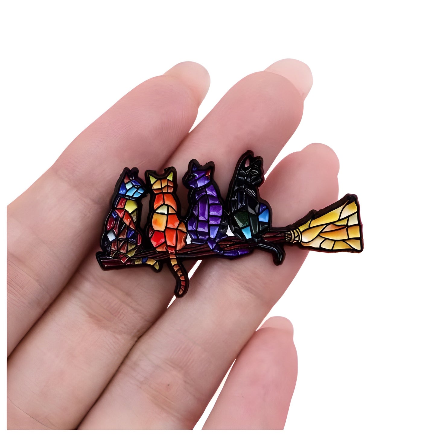 Colorful stained glass style enamel pin featuring cats sitting on a broomstick held between fingers