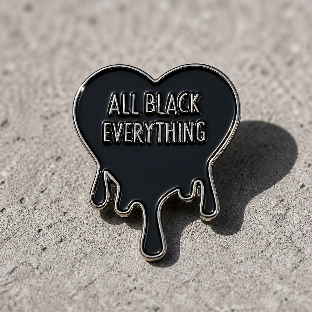 Black dripping heart enamel pin with All Black Everything text  on a concrete surface