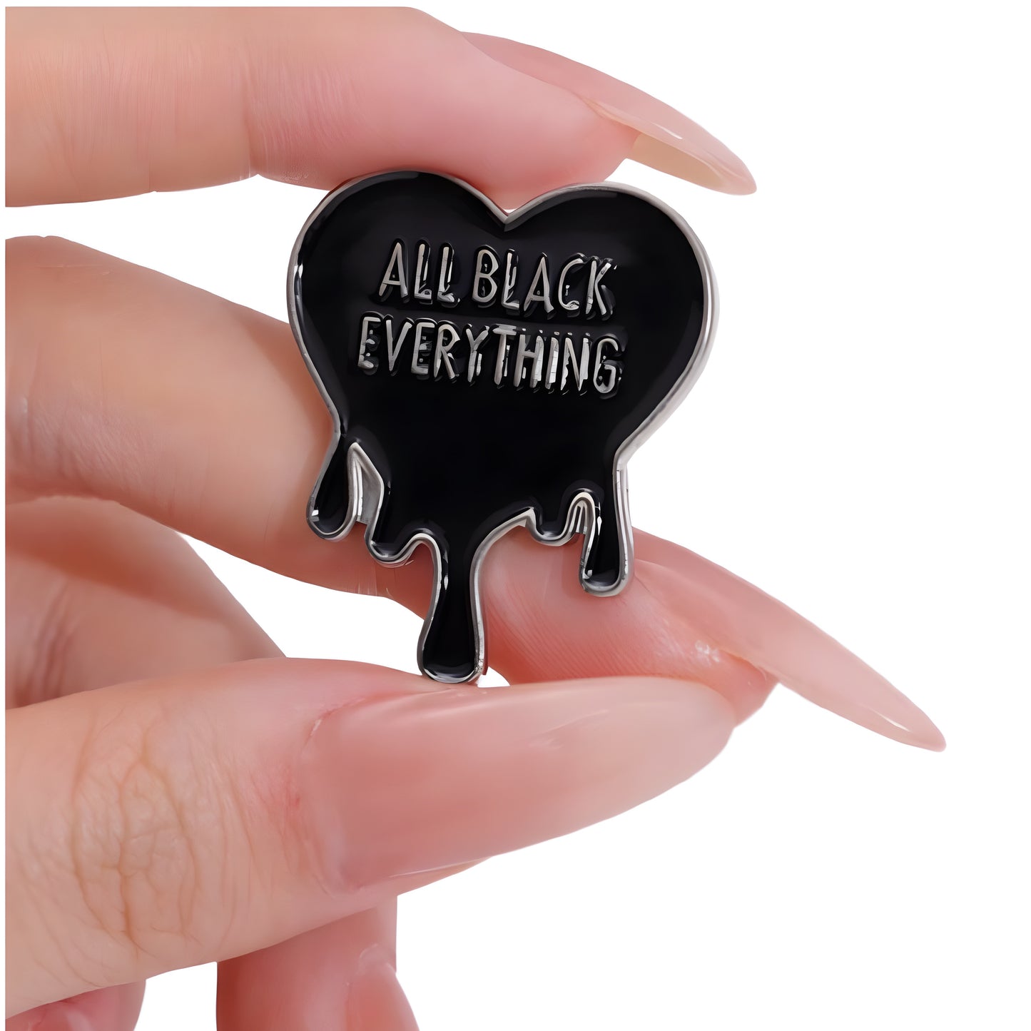 Black dripping heart enamel pin with All Black Everything text held between fingers