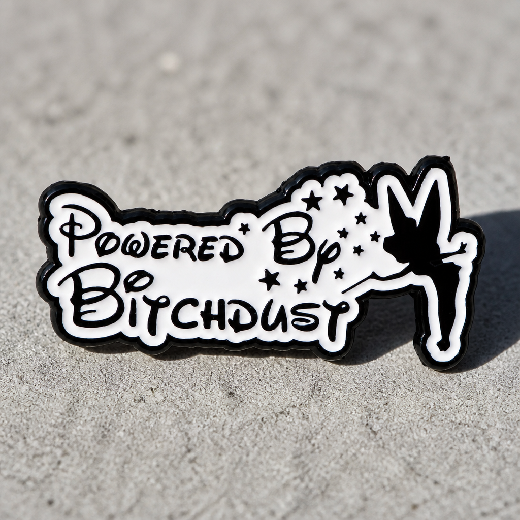 Powered by Bitchdust enamel pin with fairy-inspired magical parody artwork on a concrete surface