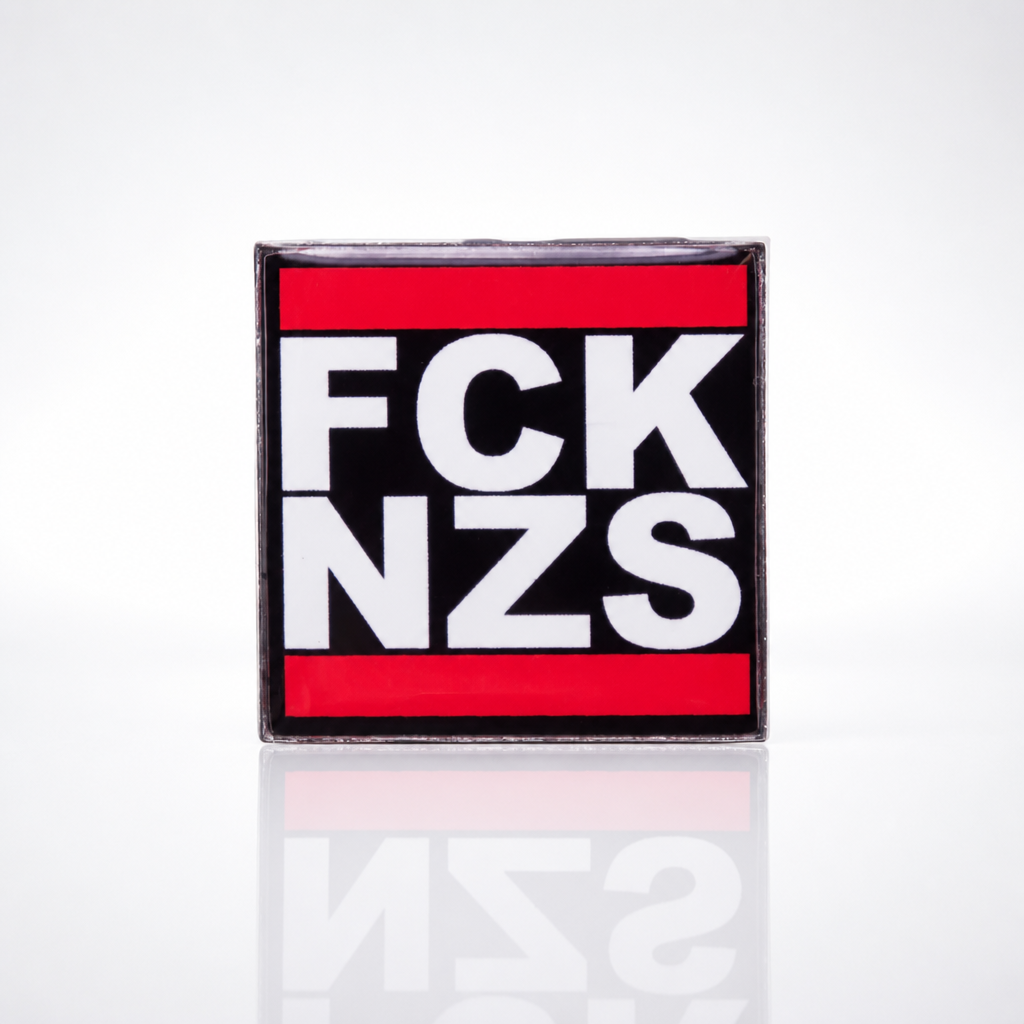Black red and white enamel pin reading “FCK NZS”