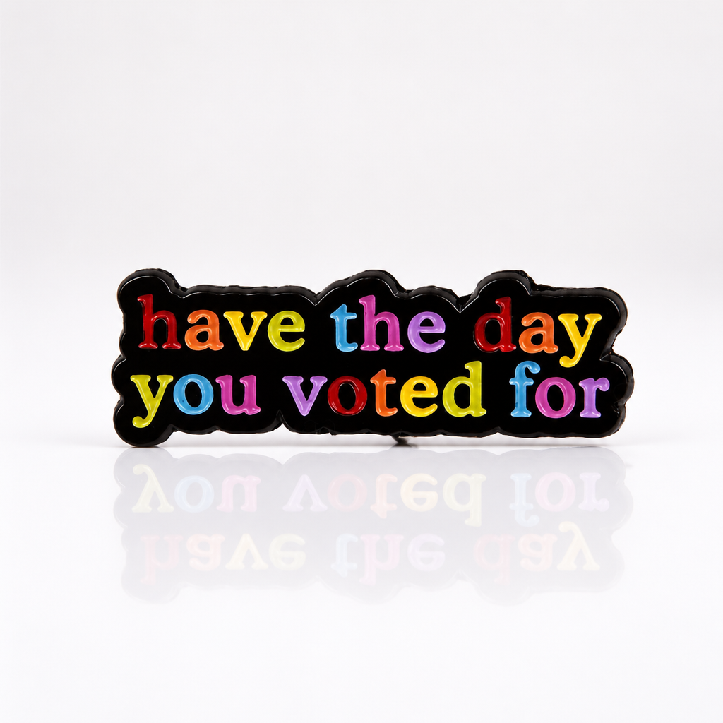 Rainbow enamel pin with “Have The Day You Voted For” text on black background