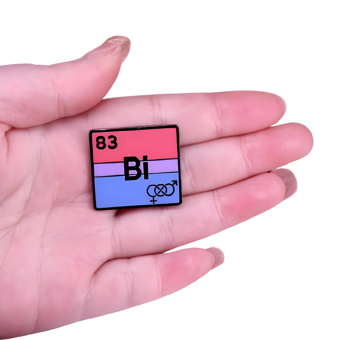 Bisexual pride enamel pin designed like a periodic table element with pink purple and blue flag colors held in a hand