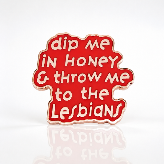 Pink enamel pin with the phrase “Dip Me in Honey & Throw Me to the Lesbians”