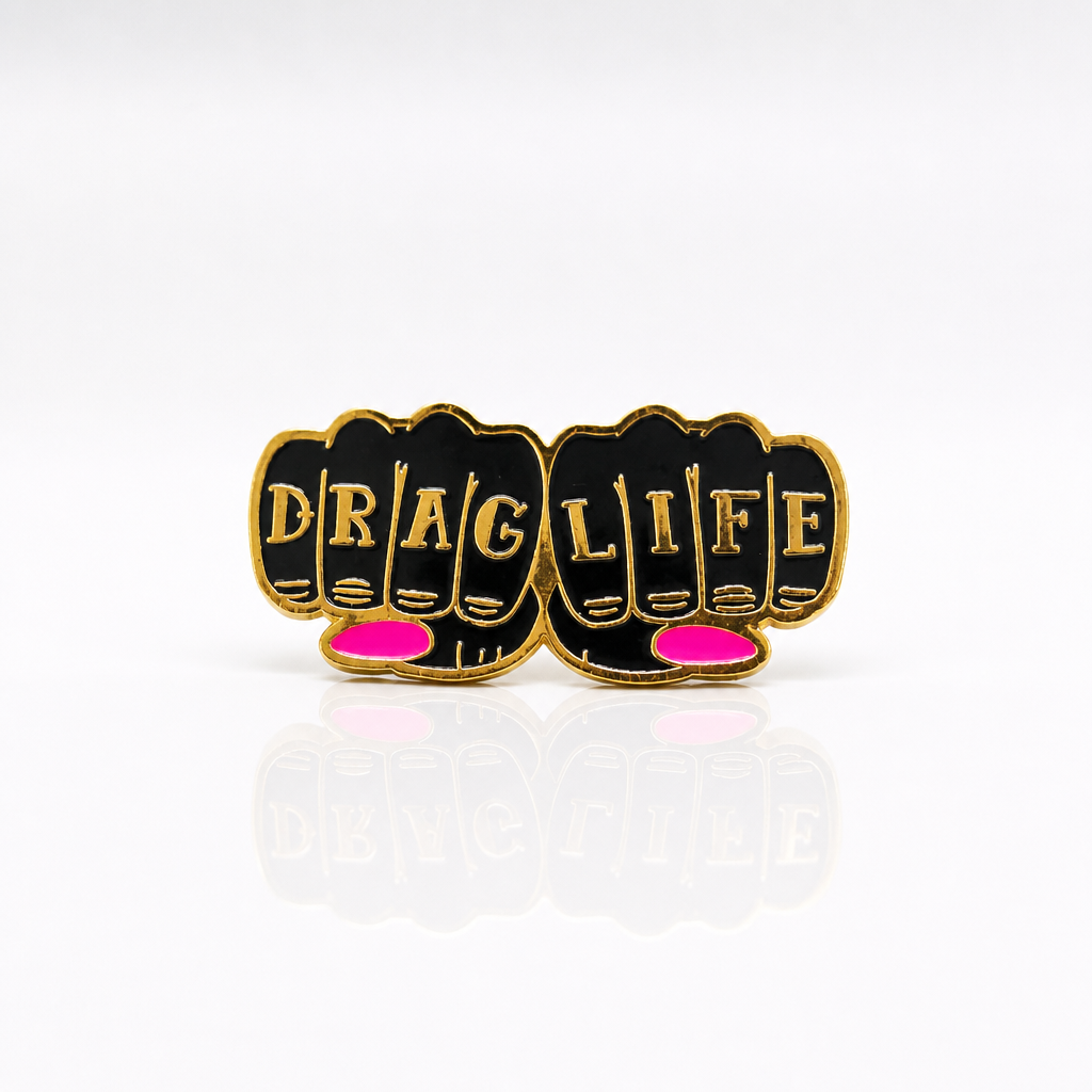 Drag Life enamel pin featuring gold-tone knuckle lettering with pink accent details