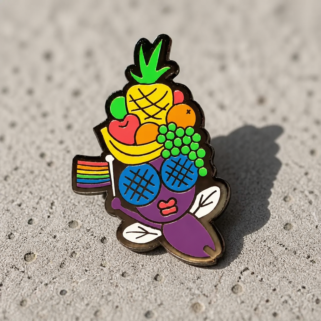 Fruit Fly enamel pin featuring a colorful fruit-inspired fly with rainbow wing detail on a concrete surface