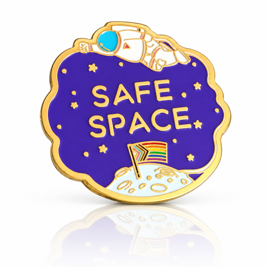 Gold hard enamel Safe Space pin with astronaut, stars and a Progress Pride flag planted on the moon.