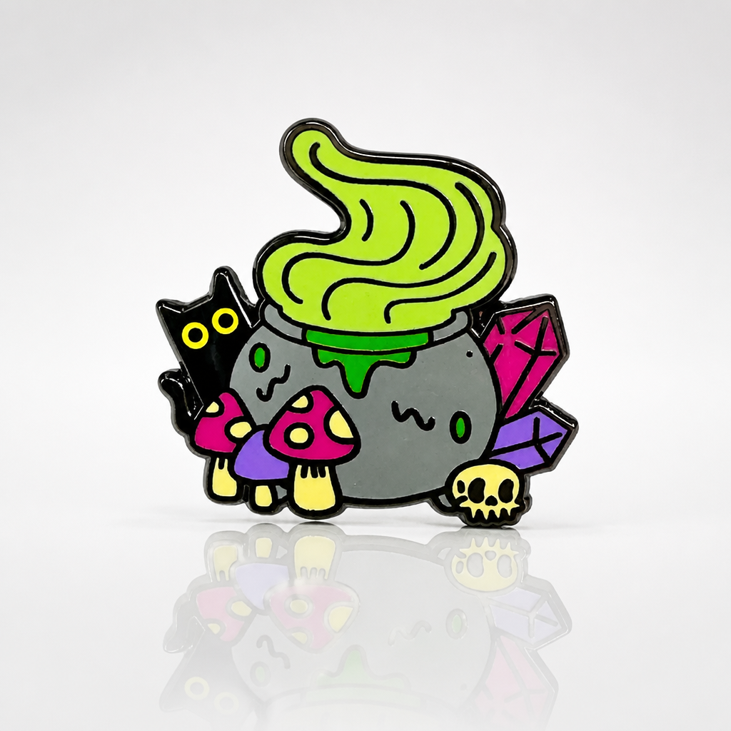 Witchy Cauldron enamel pin featuring a bubbling green cauldron, black cat, crystals, mushrooms, and skull details