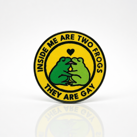 Hard enamel pin featuring two green frogs kissing with the phrase Inside Me Are Two Frogs They Are Gay