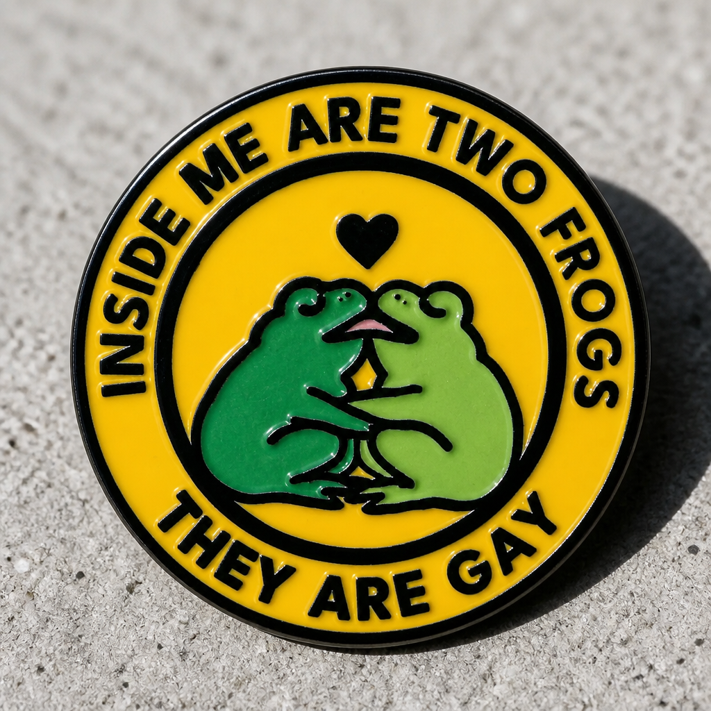 Hard enamel pin featuring two green frogs kissing with the phrase Inside Me Are Two Frogs They Are Gay on a concrete background