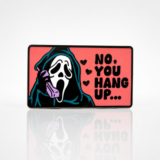 Hard enamel pin featuring a masked horror movie caller holding a pink telephone with the phrase No You Hang Up