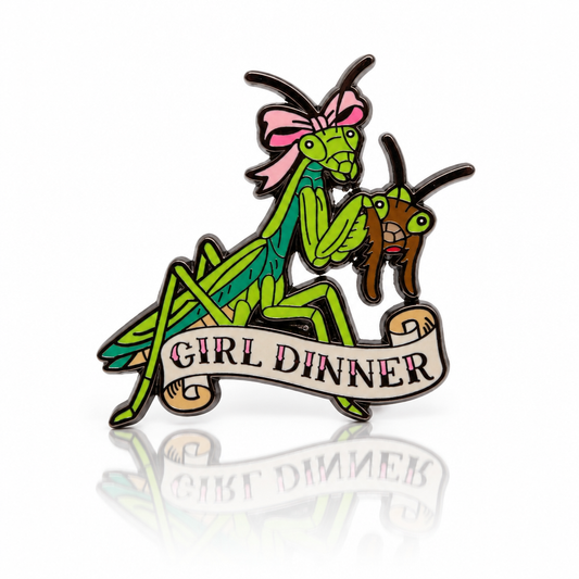 Girl Dinner hard enamel pin featuring a green praying mantis with a pink bow holding another mantis head