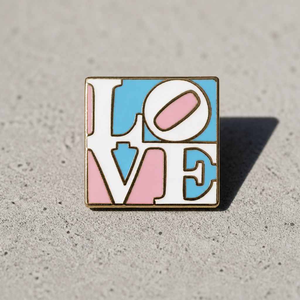 Heart-shaped transgender pride enamel pin with blue pink and white stripes and Love lettering on a concrete background