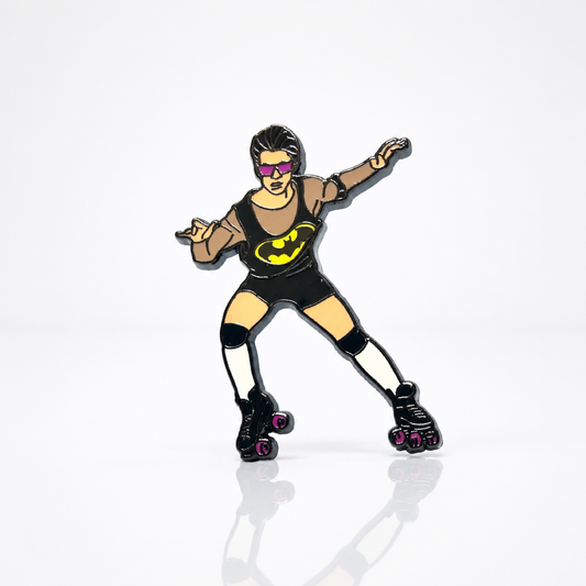 Hard enamel pin featuring a retro roller skater wearing sunglasses and a black outfit with roller skates in a playful disco-inspired design